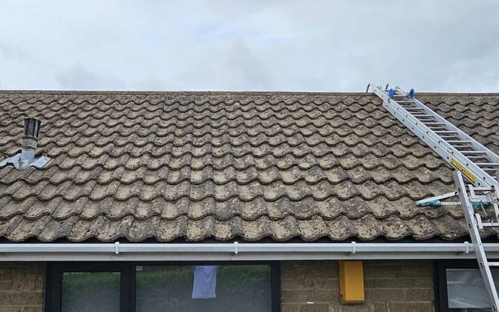 The same bungalow roof cleared of moss, tiles back to their own colour