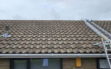 The same bungalow roof cleared of moss, tiles back to their own colour