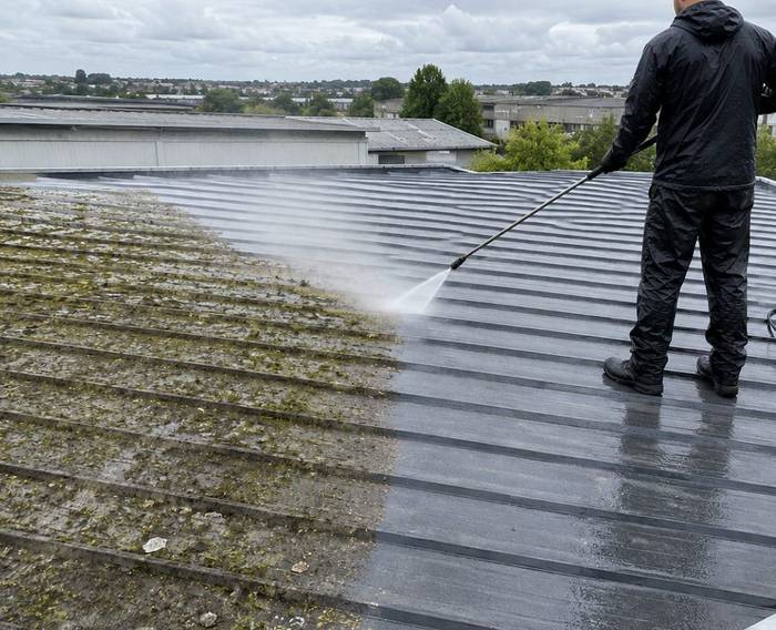 A commercial roof being soft washed