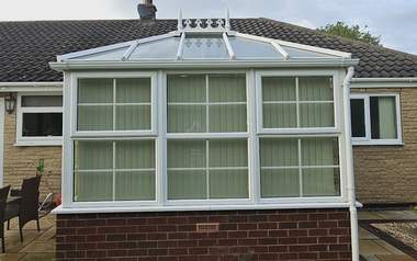 A conservatory with a glass roof and frames cleaned back to white