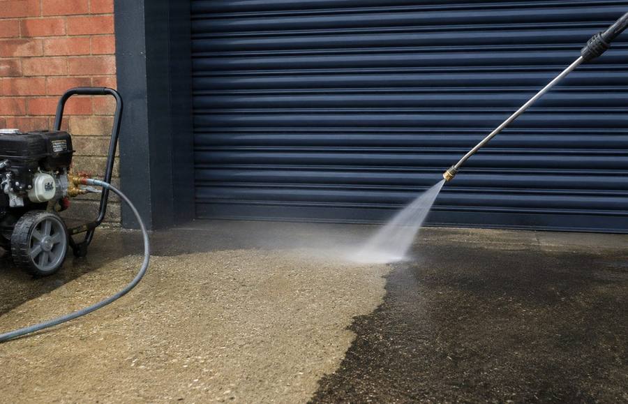 A forecourt being pressure washed with a wide fan of water