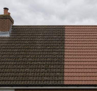 A grey tiled roof half cleaned showing the difference