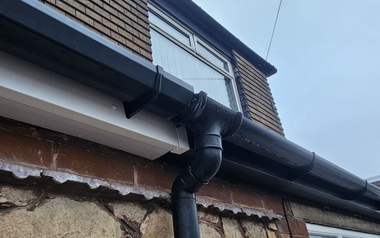 A cleaned gutter and fascia line along a roof