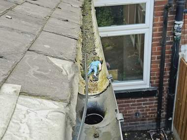 Moss being cleared from a gutter by hand