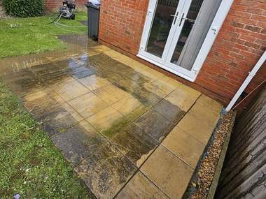 Indian sandstone patio part way through being pressure washed