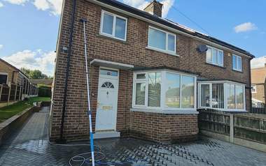 A house frontage being soft washed with the pole and hose set up
